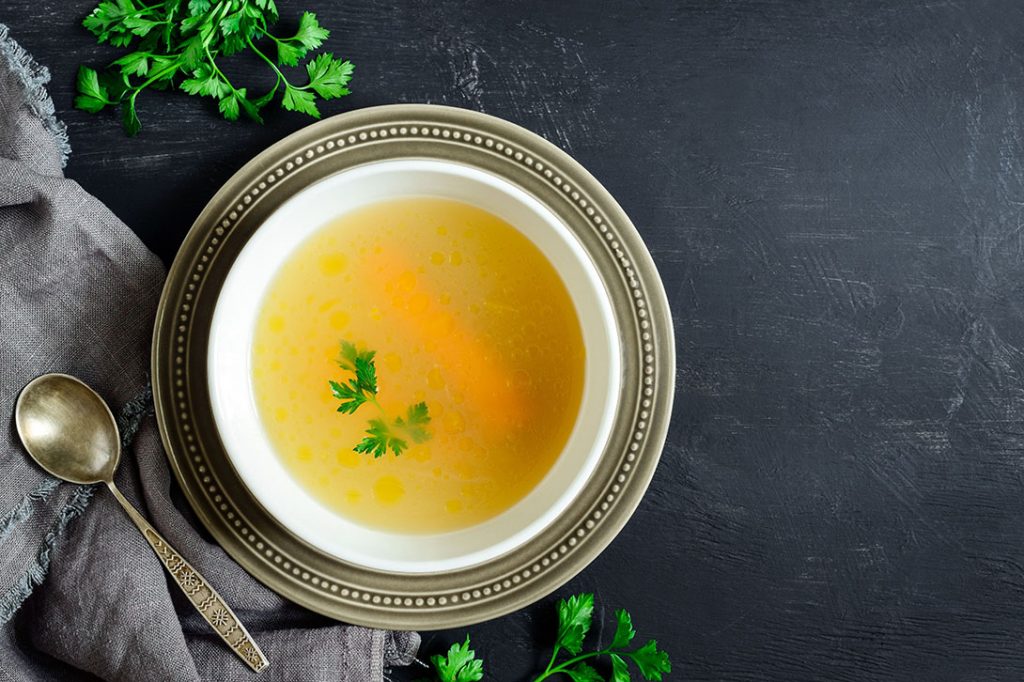 a bowl of chicken broth on a table